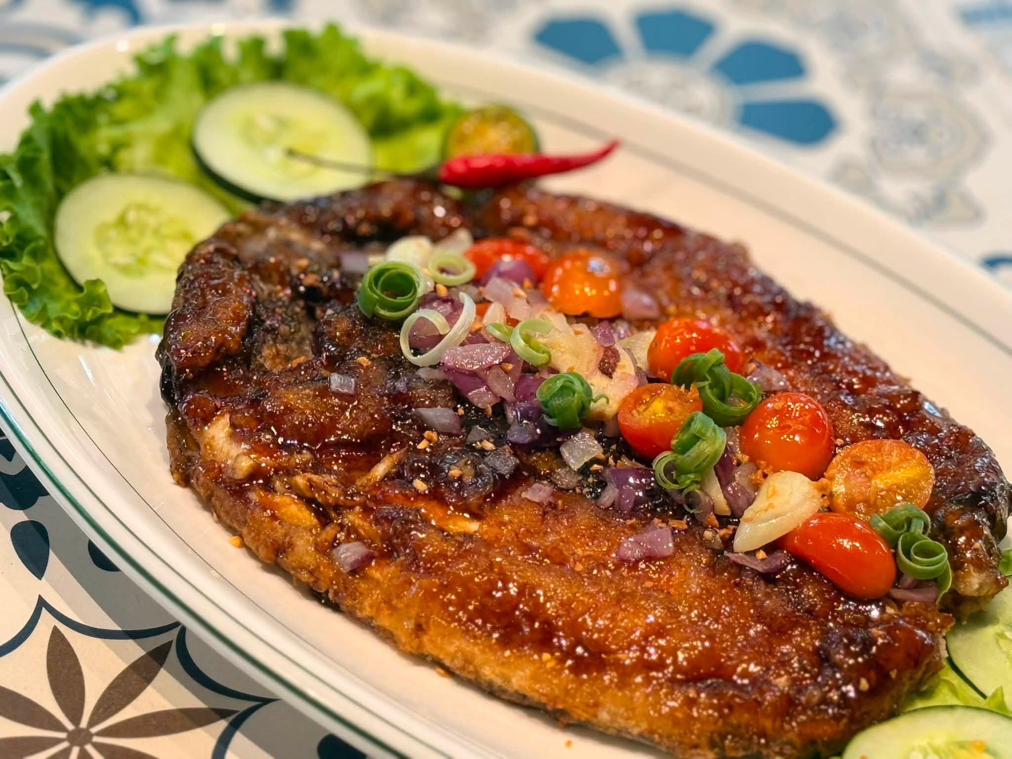 Glazed boneless bangus topped with tomatoes, onions and scallions